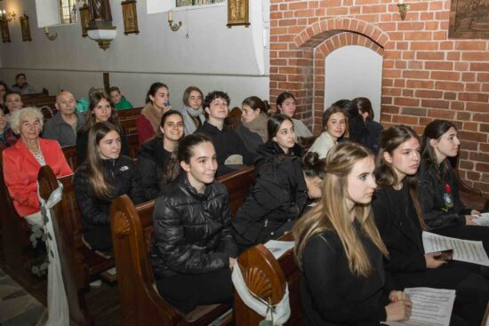 Siedzący w ławkach kościelnych chórzyści z Veus -Cor Infantil Amics de la Unió z Katalonii