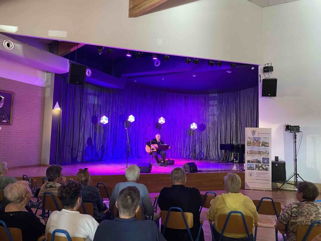 Artysta z gitarą występujący na scenie oraz publiczność