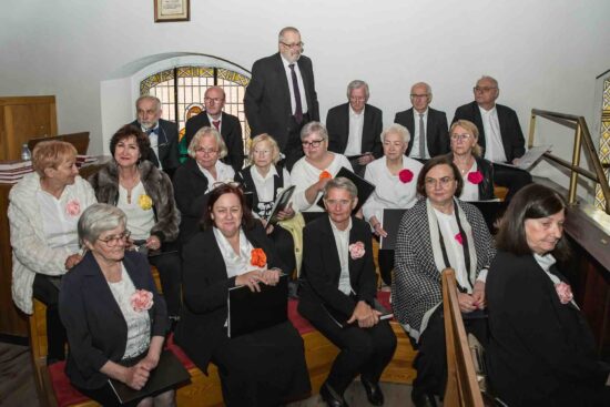 Chór Mieszany Vocantes z dyrygentką, siedzą na ławkach w kościele