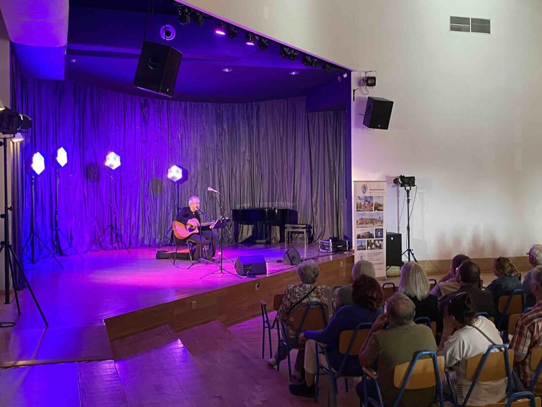 Artysta z gitarą występujący na scenie oraz publiczność