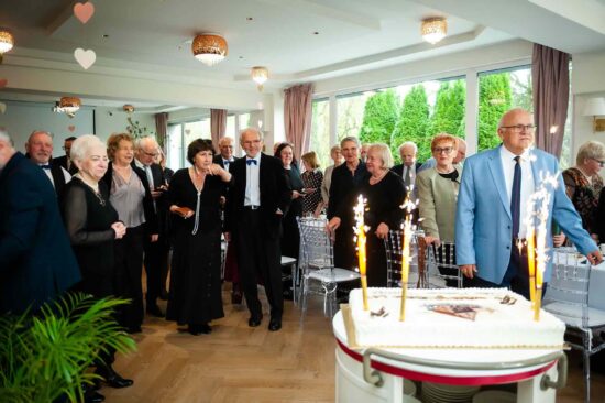 Tort z palącymi racami w tle uczestnicy spotkania w restauracji