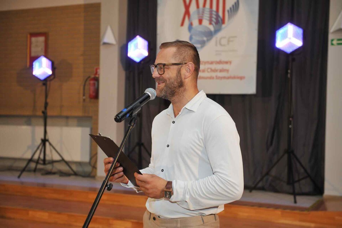 Mężczyzna przy mikrofonie, baner festiwalowy w tle