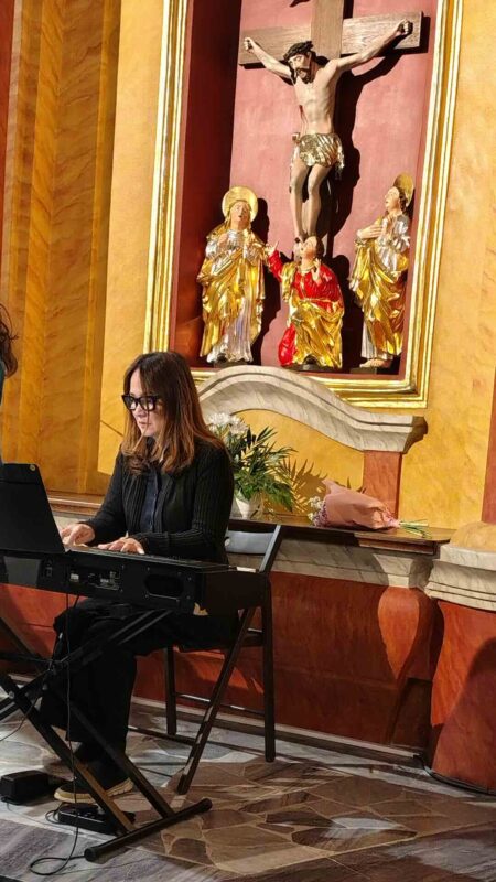 Kobieta, akompaniatorka siedzi za instrumentem klawiszowym i gra