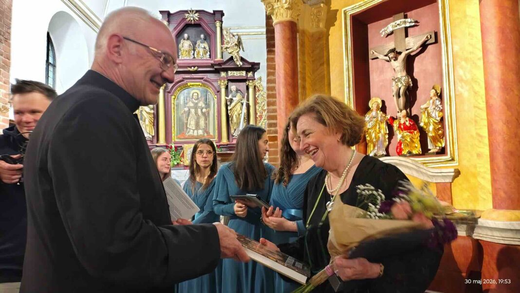 ks. Sławomir Jessa składa gratulacje i wręcza książkę dyrygentce chóru Annie Tilgi