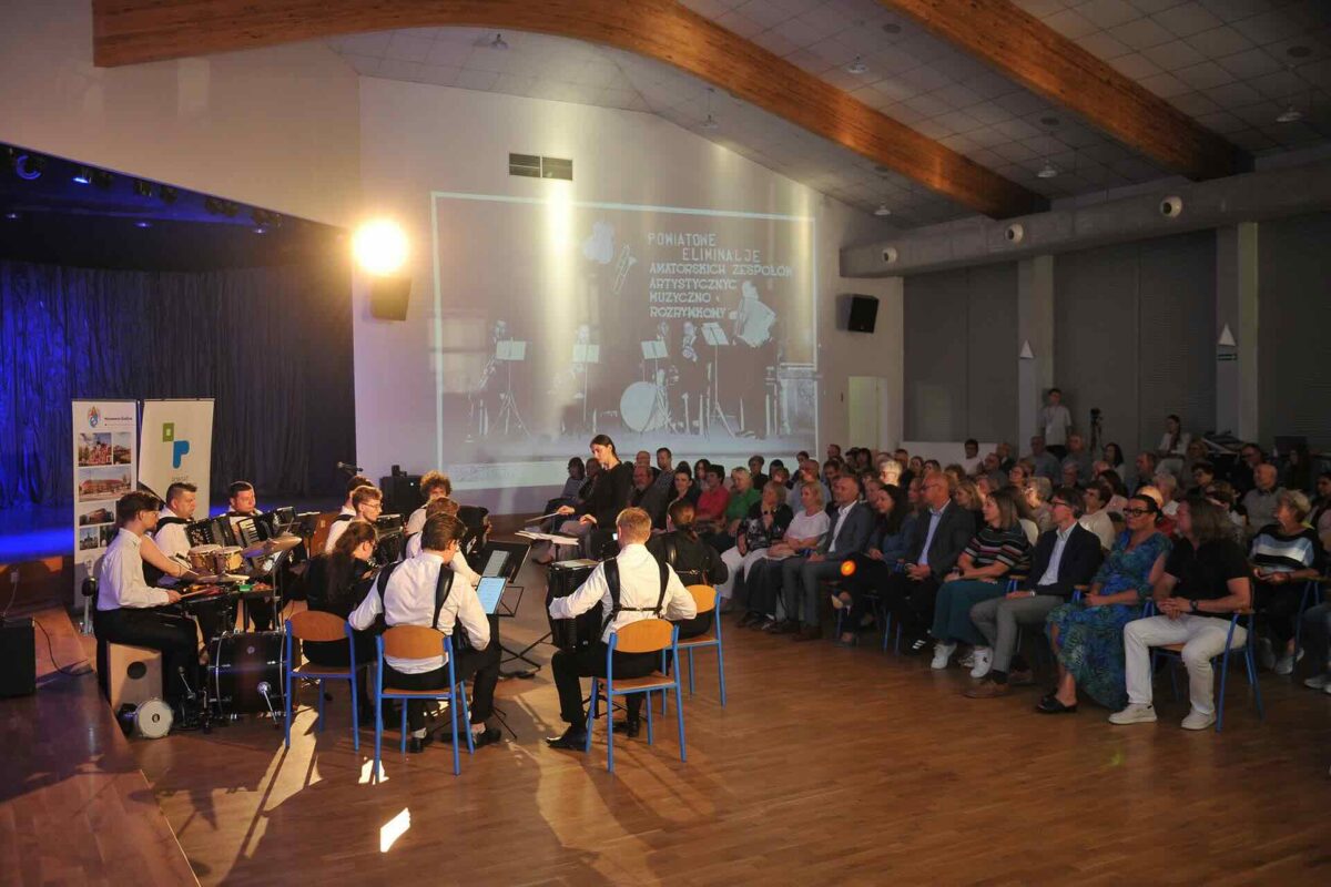 Zespół akordeonowy z dyrygentem na scenie, publiczność