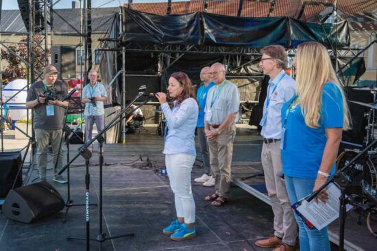 Na scenie przy mikrofonie stoi burmistrz Justyna Radomska z tyłu stoją dyrektor CkiS Marcin Stroemich, ks. proboszcz Sławomir Jessa, zastępca burmistrza Marcin Buliński